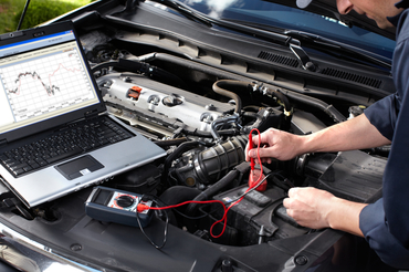 Professional bi-directional scan tool and laptop diagnostics on a vehicle engine
